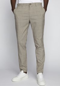 beige ruudulliset housut, joissa on etutaskut, kapeampi malli ja nappisulku, yhdistetty valkoisiin lenkkareihin. Sileä kangas.