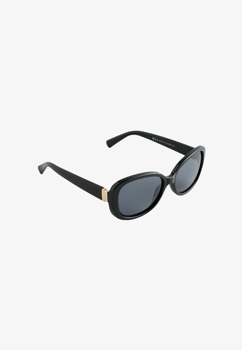 Lunettes de soleil noires avec une monture épaisse et ovale et des verres foncés. Présentent des accents métalliques dorés là où les branches se connectent à la monture.