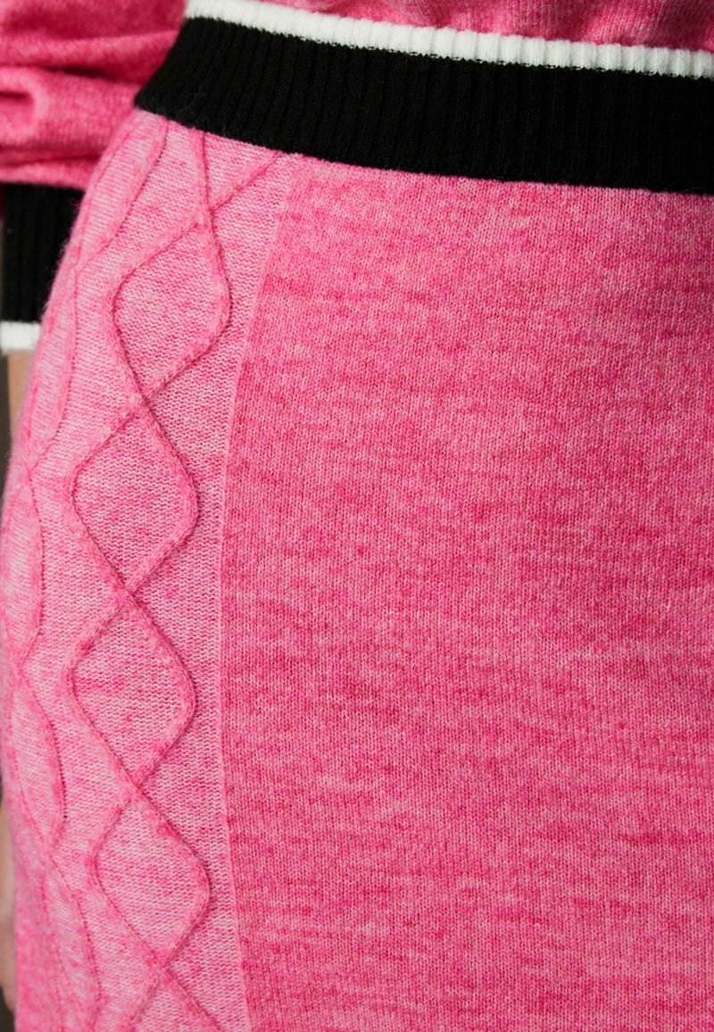 Fuksia roosa, kootud legginsid, millel on tekstureeritud teemantmustrit külgedel ja must ribikreen valgete triipudega.