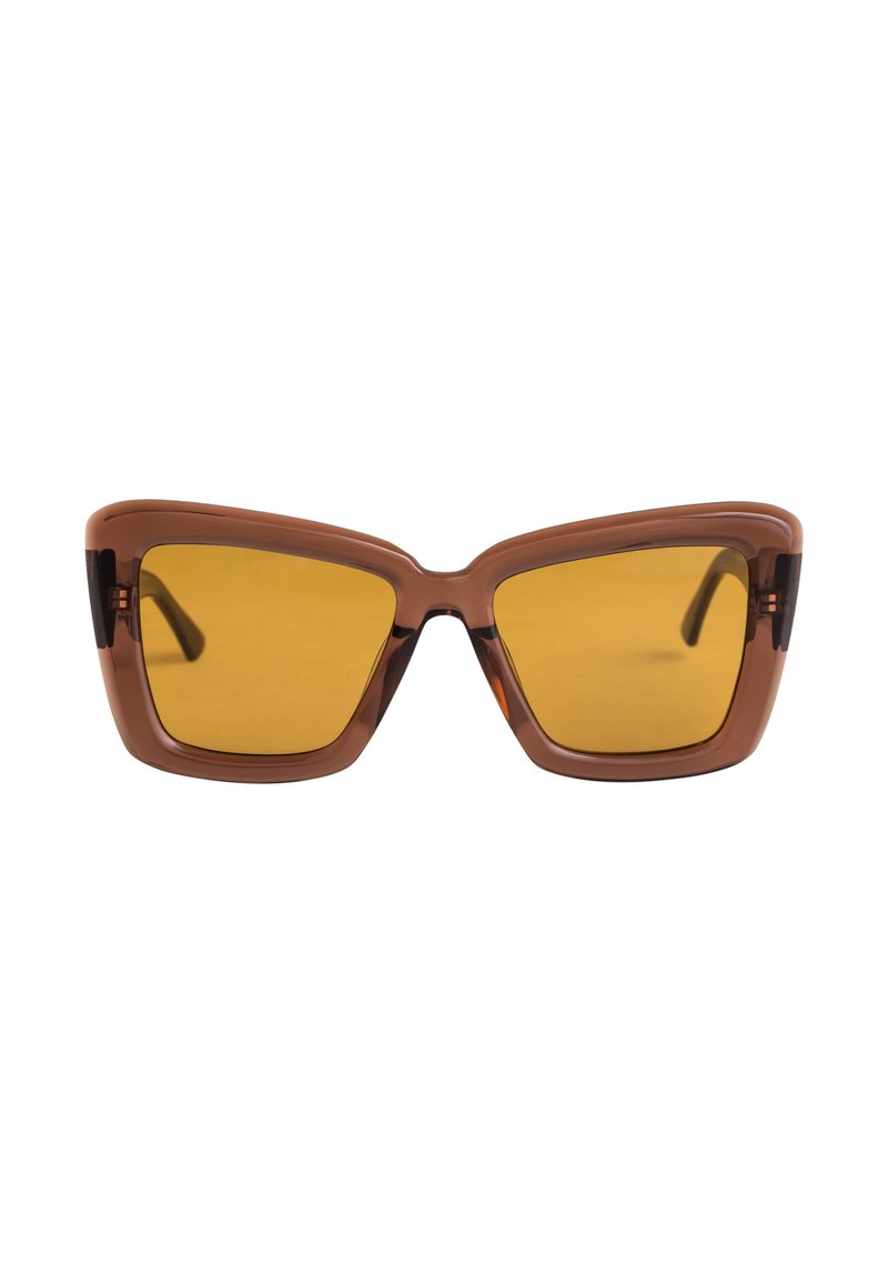 Gafas de sol marrones en forma de ojo de gato con lentes amarillos y un marco grueso. Presentan ángulos pronunciados y un acabado brillante en la parte frontal.