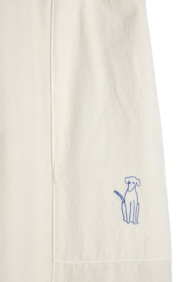 Tissu blanc avec un petit dessin en ligne bleue simple d'un chien assis près du coin inférieur droit.