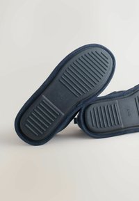 Tumedad sinised sussid tekstureeritud kummist tallaga, pehme kangast ülaosa ja äärte õmblemise aktsent. Suurus märgitud kui 8/42.