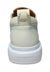 Weiße Leder-Sneaker mit glatter Textur, featuring ein goldgestempeltes Logo auf der Ferse und einer weißen Gummisohle mit Nahtakzenten.