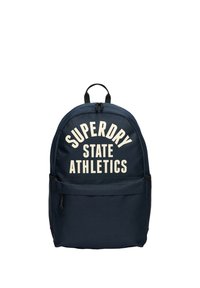 Marineblå stofrygsæk med hvid tekst "SUPERDRY STATE ATHLETICS", buet design, topstrop og lynlåslomme foran.