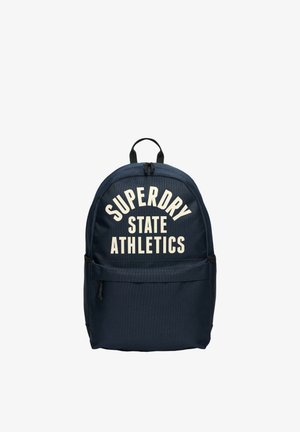 Navy blue fabric backpack with white "SUPERDRY STATE ATHLETICS" text, curved design, top handle, and front zippered pocket.