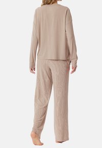 Beige long-sleeve top with a relaxed fit and soft texture, paired with light beige pants featuring a subtle, wavy line pattern.