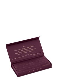 Fioletowe prostokątne opakowanie z złotym tekstem i niebiańskimi grafikami. Zawiera jedwabne maski na oczy, złożone wewnątrz, zaprojektowane do pielęgnacji skóry.