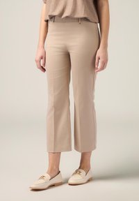 Beige, op maat gemaakte cropped broek met een gladde textuur, voorzien van een middelhoog tailleband en zijzakken, gecombineerd met crèmekleurige loafers.