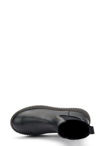 Botín de cuero negro hasta el tobillo con punta redondeada, paneles laterales elásticos y una suela de goma texturizada que presenta un borde elevado a lo largo del contorno.