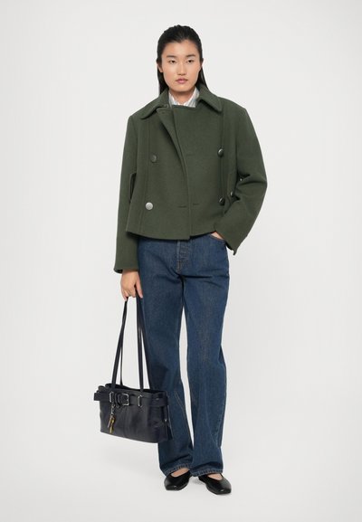 Green woolen peacoat with silver buttons, cropped design, paired with blue wide-leg jeans and a black handbag with a belt detail.