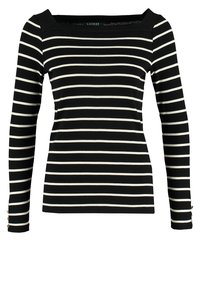 Chemise noire à manches longues avec des rayures blanches horizontales et un col carré, ornée de petits boutons dorés sur les poignets des manches.