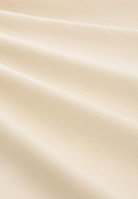 Tejido beige texturizado con un sutil brillo, que presenta cortinas suaves y fluidas con una apariencia ligera. Adecuado para diversas aplicaciones textuales.