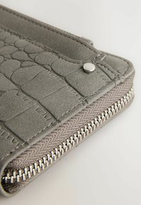 Grijze faux leren portemonnee met krokodillenstructuur, zilverkleurige hardware en een ritssluiting die langs de rand is afgewerkt.