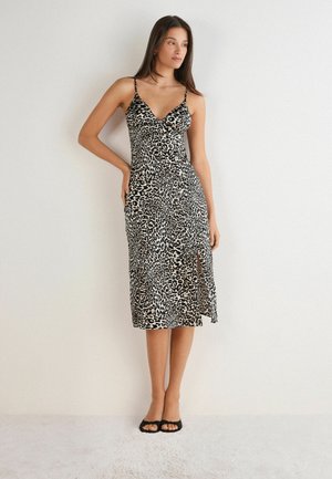 Zwart en beige luipaardprint midi-jurk met dunne bandjes, V-hals en een zijsplit, gemaakt van een lichtgewicht, glad materiaal. Zwarte sandaaltjes.