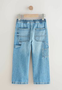 Pantaloni din denim de culoare bleu deschis, cu un Croi lejer, având un elastic la talie, două buzunare la spate și un buzunar lateral cu dungi orizontale.