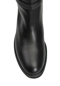 Czarna skórzana botka sięgająca kostki z gładką powierzchnią, zaokrąglonym noskiem i niską, teksturowaną gumową podeszwą. Posiada delikatne zagniecenie u góry.