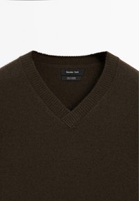 Maglione in cashmere a V nel colore marrone scuro. Tessuto morbido con colletto e orlo a coste. L'etichetta recita "Massimo Dutti, 100% cashmere, made in Cambodia."