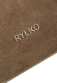 Bruine suède oppervlakt met daarop in reliëf gedrukt zilveren letters "RYŁKO" prominent weergegeven. Het materiaal heeft een zachte textuur met een matte afwerking.