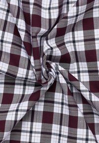 Tessuto di cotone con un motivo a quadri bordeaux e bianchi. Presenta linee incrociate di spessore variabile, creando un aspetto texturizzato.