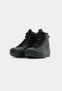 Zwarte hoge schoenen met een gestructureerde rubberen zool, versterkte neus en vetersluiting. Gemaakt van synthetisch materiaal, met trekflappen op de hiel.