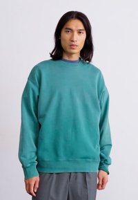 Teal sweatshirt med rund hals, ribbede manchetter og kant, der har en afslappet pasform og glat, let tekstureret materiale.
