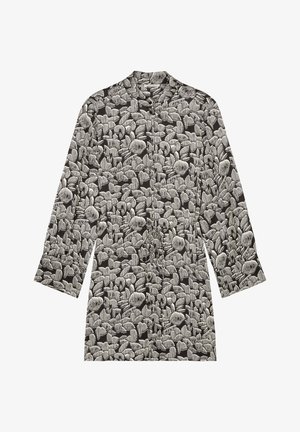 Veste à motif noir et blanc avec un col, des manches longues et une coupe décontractée. Présente des formes abstraites et des rayures verticales.