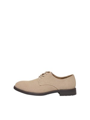 Beżowe zamszowe męskie eleganckie buty sznurowane z niską czarną podeszwą i zaokrąglonym noskiem, widok z boku na białym tle.
