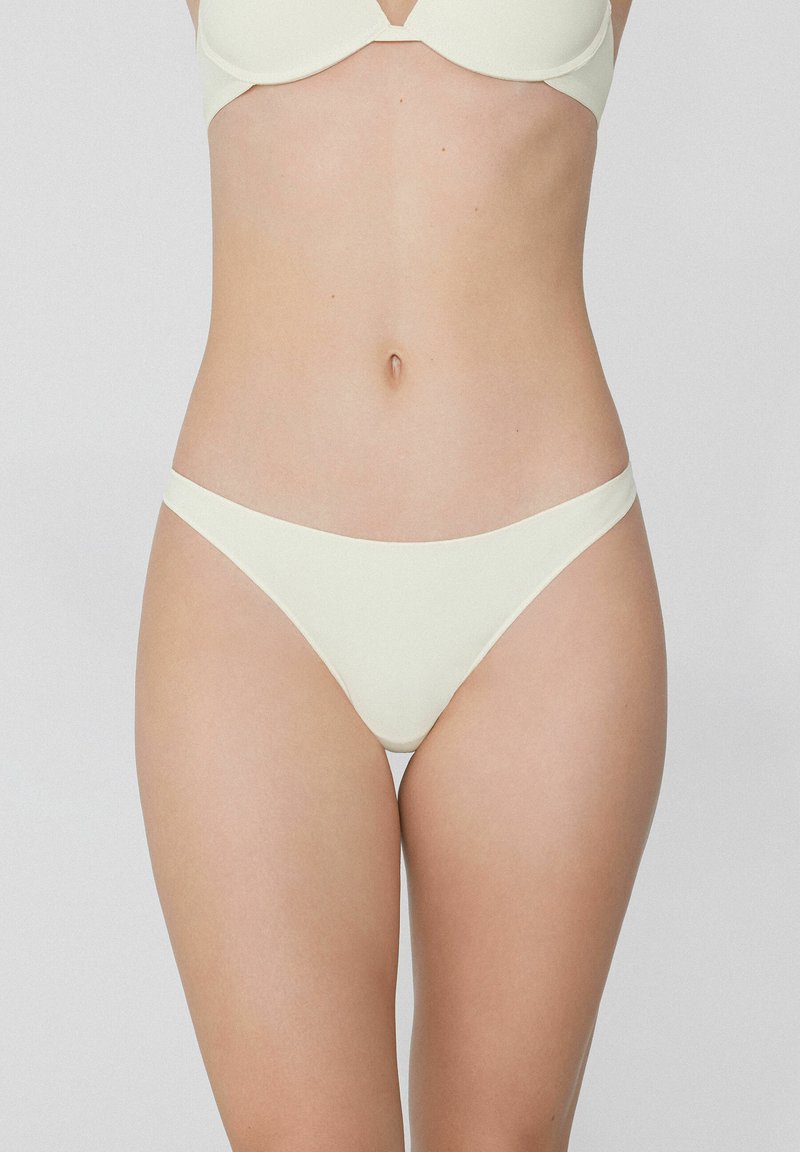 Hellbeige Bikini-Hose mit glatter Textur, die einen niedrigen Schnitt und ein minimales Bunddesign aufweist und hinten vollen Schutz bietet.