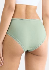 Högmidjade damunderkläder i mjukt, ljusgrönt tyg. Utrustad med delikat spetskant längs midjebandet och benöppningarna.