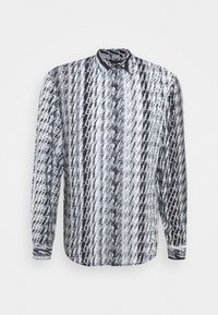 Camicia a maniche lunghe con motivo a zigzag bianco e nero e testo ripetuto. Realizzata in tessuto leggero, presenta una chiusura frontale con bottoni e un colletto.