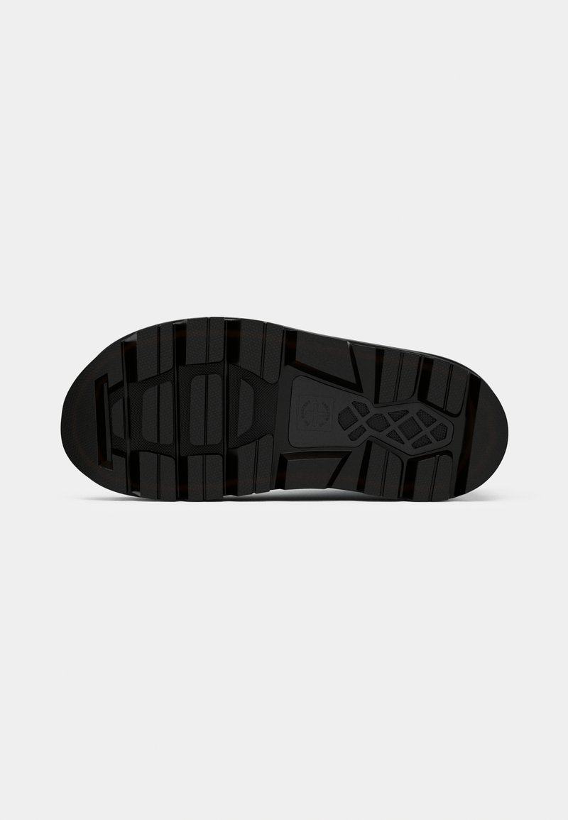 Semelle de sneaker en caoutchouc noir avec une surface texturée et des motifs de semelle distincts pour une bonne adhérence. Comprend un logo au centre.