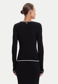 Maglione nero a maglia con maniche lunghe, caratterizzato da una rifinitura bianca lungo il collo e i polsini, e un accento del logo dorato sul retro.