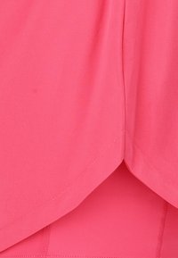 Vaalea urheilupaita, jossa on kerroksellinen muotoilu, sileä kangas ja pehmeä rakenne, helma, jossa on pieni kaarevuus, sekä yläompeleet korostavat yksityiskohtia.