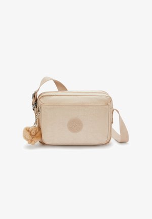 Borsa a tracolla color crema realizzata in materiale morbido, con logo rotondo, chiusure con zip e un portachiavi a forma di animale in peluche.