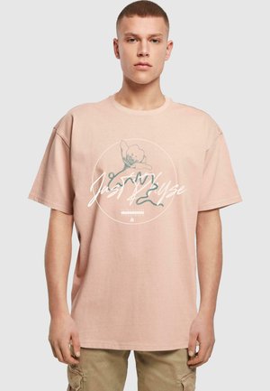 Light pink cotton t-shirt with a round graphic featuring a flower and text, loose fit, short sleeves, ribbed neckline.