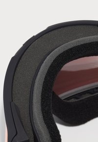 Detalii ale căștii cu umplutură din spumă stratificată, hardware negru și un interior neted și reflectorizant în nuanțe de gri și roz.