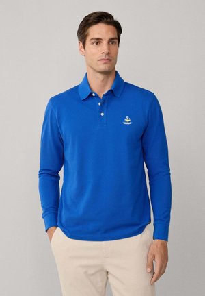 Blauw polo-shirt met lange mouwen en een kraag, met een klein geborduurd logo op de linkerborst en geribbelde manchetten.