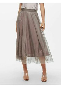 Jupe midi plissée en taupe clair avec une ceinture en satin ; fabriquée en tissu transparent et texturé qui ajoute des couches et du mouvement. Sandales transparentes.