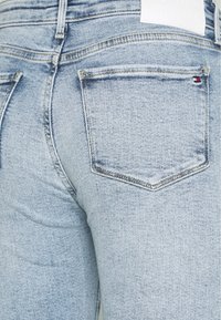 Ljusblå denimjeans med en klassisk femfickdesign, subtila slitningar och en logotypmärke på bakre delen av midjebandet.