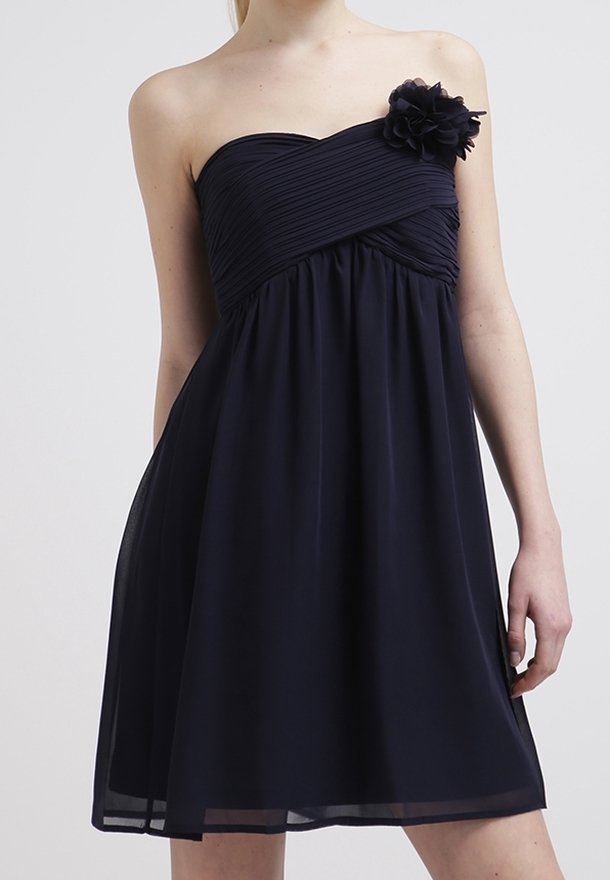 Robe noire bustier plissée, jupe froncée et grande fleur en tissu sur la poitrine gauche.