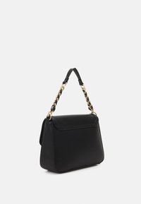 Sac en cuir noir avec un design structuré, doté d'une courte poignée noire et d'un accent en chaîne dorée. Texture lisse et style minimaliste.