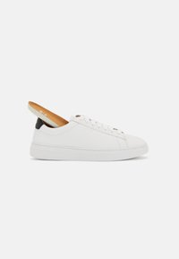Hvide lædersneakers med rund tå, flad sål og snørebåndsdesign. Har en tan indersål og en kontrasterende bagkant.
