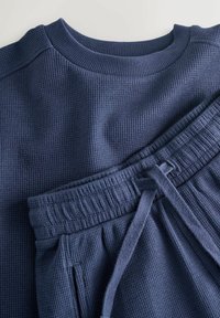 Top a maniche lunghe a trama waffle di colore blu navy scuro con scollo rotondo e pantaloni della tuta abbinati con vita elastica e coulisse.