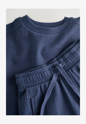 Haut à manches longues texturé en nid d'abeille de couleur bleu marine foncé avec un col rond, accompagné d'un pantalon de survêtement assorti doté d'une taille élastique et d'un cordon de serrage.