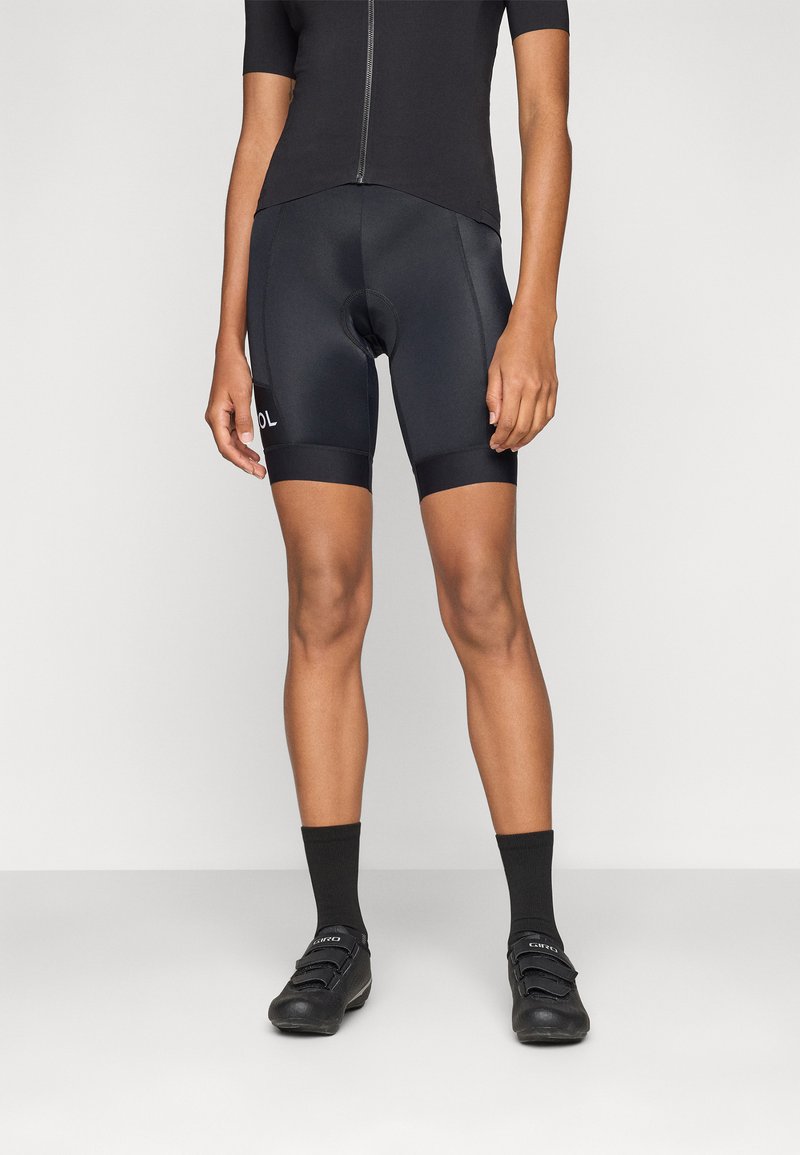 Sorte sykkelshorts med fukttransporterende stoff, polstret sete og elastiske bånd ved bena. Kombinert med sorte sykkelsko og sokker.