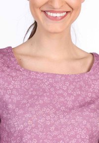 Rosa Bluse mit floralem Muster, einem quadratischen Ausschnitt, kurzen Ärmeln und einem weichen, strukturierten Stoff. Das Design zeigt kleine, zarte weiße Blumen.