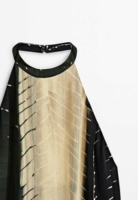 Robe sans manches à col montant ; tissu beige et noir avec des lignes et des formes abstraites, fabriquée en matériau léger et texturé.