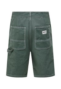 Short en jean vert foncé avec coutures blanches, deux grandes poches arrière, une petite boucle porte-outils sur le côté et une étiquette de marque sur la poche droite.