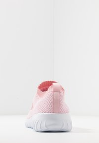 Růžové nazouvací boty s texturovaným pleteným svrškem, elastickým límcem a poutkem na patě. Bílá flexibilní podrážka s vlnitým vzorem. Minimalistický design.