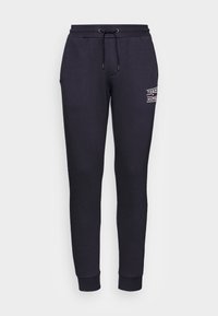 Zwarte sweatpants van zachte stof hebben een elastische tailleband met een trekkoord, taps toelopende benen en een witte logo-opdruk op de heup.